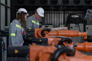 Fototapeta premium Engineer standing by robotic arm and operating machine in industry factory, technician worker check for repair maintenance electronic operation.