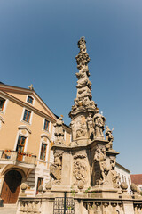Fototapeta premium Historical fountain in a public square of an old european city of Kutna Hora in Czech Republic surrounded by old buildings under a clear blue sky