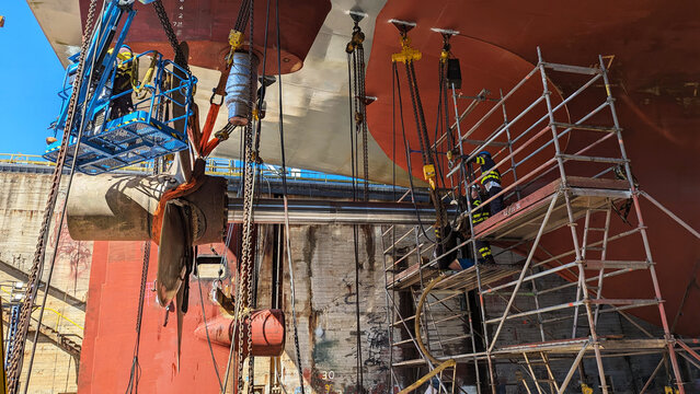 Ship Propeller Repair During Dry Dock Maintenance With Workers And Scaffolding