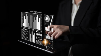 A focused businesswoman interacts with a digital tablet to engage in marketing planning, utilizing advanced data visualization and interactive charts for strategic decision-making. Impute