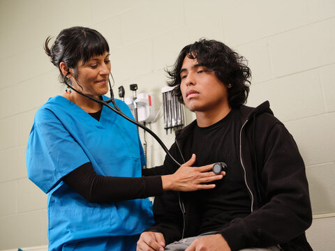 Native American nurse listens to teenage boy's heart