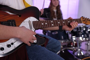 Teenage music band practicing their performance indoors, closeup