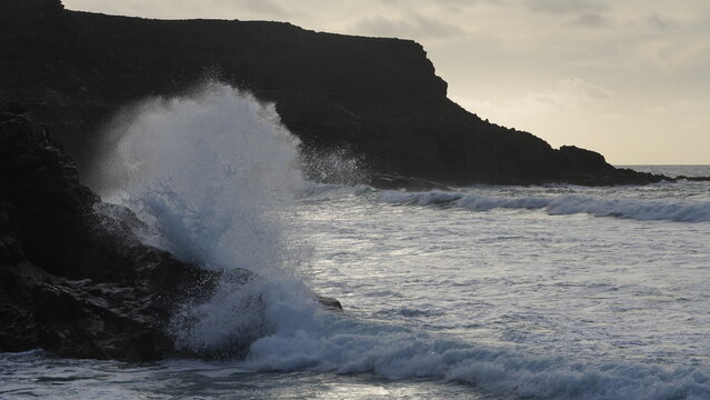 Spectacular sunset contemplating the force of the sea crashing agains the cliff