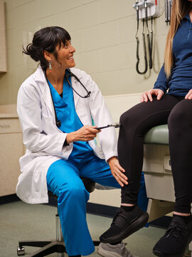 Indigenous nurse testing knee reflexes in clinic