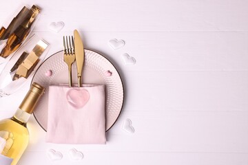 Valentine's Day. Elegant setting with cutlery, decorative hearts and wine on white table, flat lay....