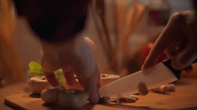 A chef's skilled hand cuts fresh porcini mushrooms with a sharp knife, preparing them for marinating and stewing, against a kitchen backdrop of ingredients, highlighting culinary expertise