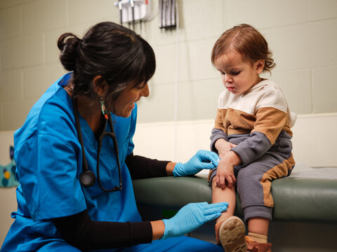 Native American nurse treats boy's knee in clinic