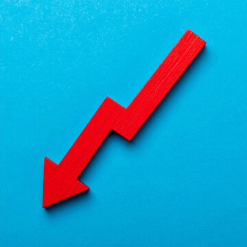Red wooden arrow pointing downward, blue backdrop. Economic downturn, business, market decline