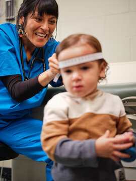 Native American nurse measures toddler's head circumference