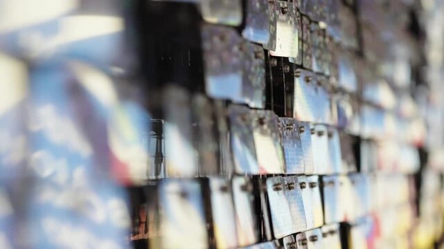 Close-up macro of colorful hanging display cards forming a textured mosaic wall, with layered rectangular tags, glossy surfaces, depth-of-field blur, and riveted holes.