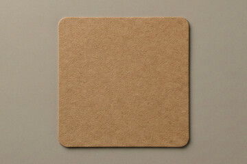 Top view of a blank square brown cardboard coaster mockup isolated on a smooth beige surface