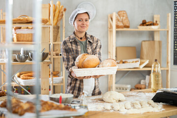 Young woman baker keep basket of baguettes, bread business production, making bread and pastries....
