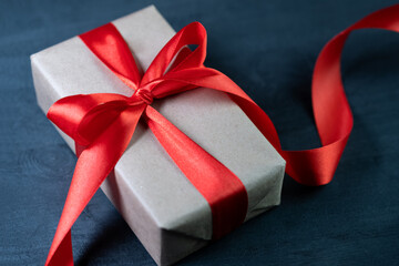 Close-up gift box with a red ribbon, wrapped in craft paper