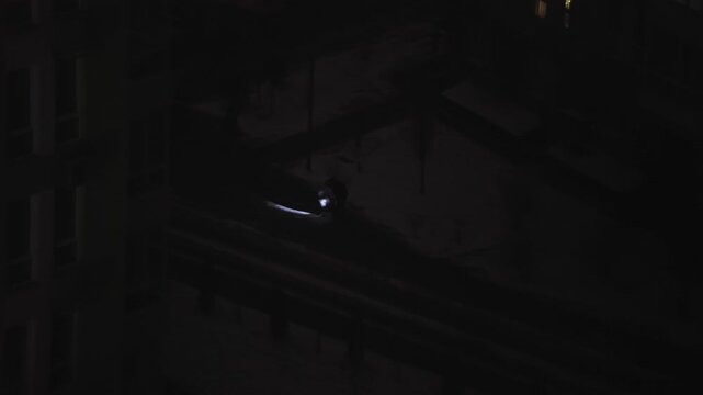 Pet owners walking their dogs with a flashlight on a cold winter evening during a citywide power outage. The city remains in complete darkness as everyday routines continue despite difficult circumsta