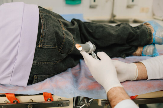 Proctologist conducts anal and rectal exam using diagnostic light.
