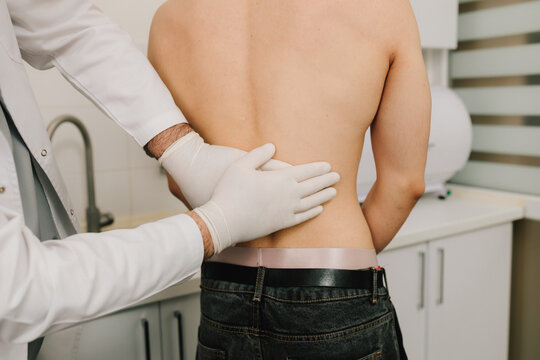 Urologist checks kidney tenderness through palpation during examination.