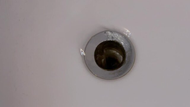 water spinning into bathtub drain forming whirlpool close view transparent clean stream simple household moment bathroom minimal scene Concept of flow and everyday routine