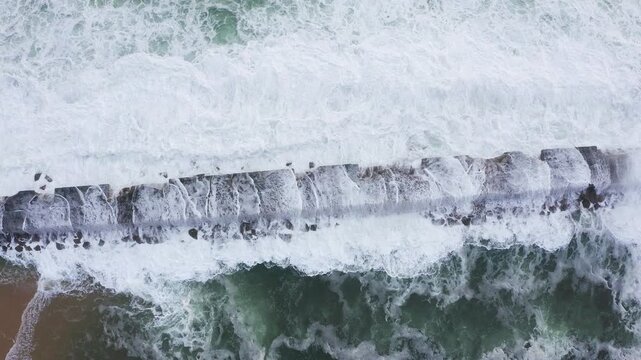 Huge waves crashing over Breakwater during winter storm Atlantic waves washing the lighthouse on Praia da Aguda sandy beach at Aguda settlement near Porto, Portugal. TOP view 4K flying drone video.