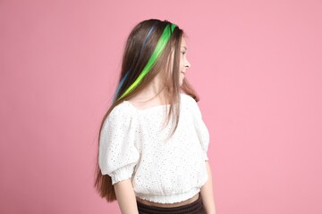 Cute girl with bright clip-in hair extensions on pink background