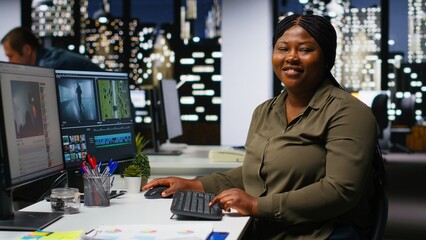 Female expert editor working in video production industry at agency office, doing color grading and creating a montage on dual monitors. Creative process with multimedia tech tools. Camera B.