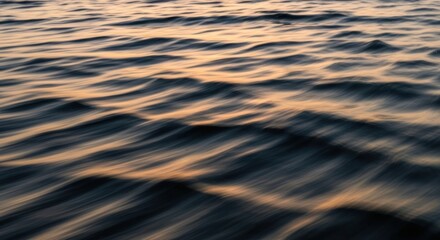 Abstract view of ocean waves reflecting golden light at sunrise or sunset