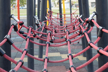 Playground rope net structure perspective view. Rope net playground structure for climbing and balance activities in city park. Children play equipment photographed without people. © Elena