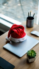 Laptop with Santa hat on desk for Christmas holiday work concept, concept for holiday business campaigns, lifestyle visuals