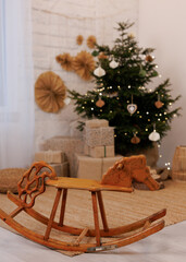 Wooden rocking horse in cozy living room with Christmas tree and gifts