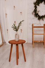 Minimalist wooden stool with vase and greenery in modern interior setting