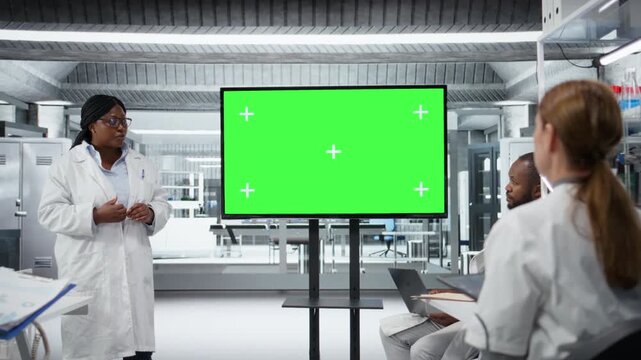 Green screen display used by biotechnology expert in lab presenting innovative DNA sequencing project to colleagues. Laboratory manager using mockup screen to do briefing for researchers, camera A