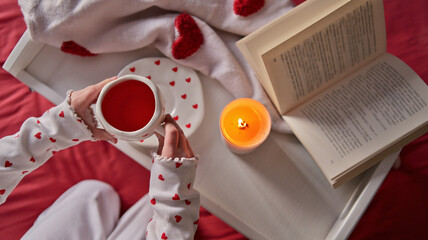 Cozy morning with a book, hot drink, and a candle, decorated with hearts