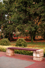 Wooden bench on stone supports in a park surrounded by greenery