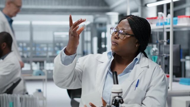 Female scientist looking at patient biopsy slide to detect abnormal cellular growth. African american woman preparing microscope in hospital lab for diagnostic confirmation, camera B