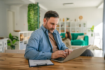 Obraz premium Happy man working remotely from home enjoying family time