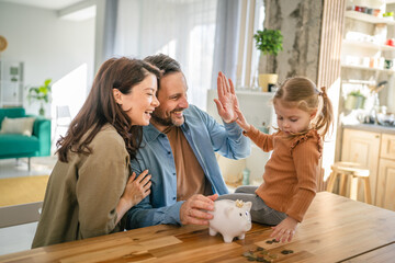 Family saving money in piggy bank, high five for financial success