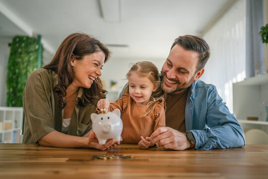 Family teaching child about saving money with piggy bank