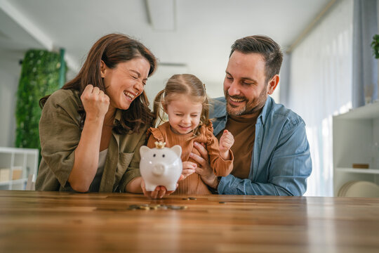 Family teaching child about saving money with piggy bank