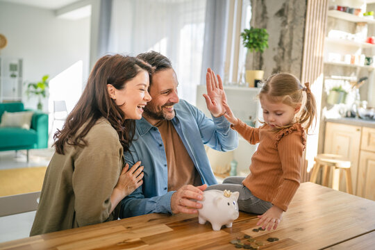 Family saving money in piggy bank, high five for financial success