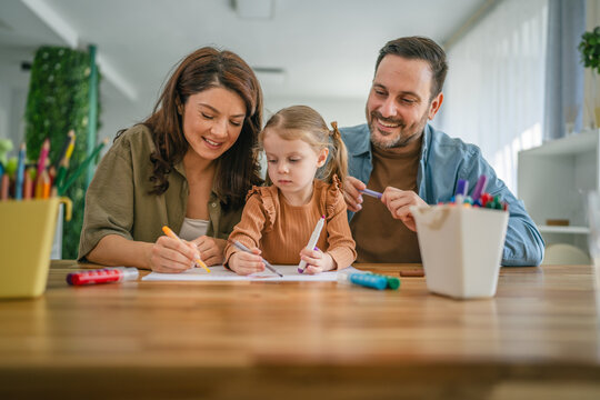 Happy family enjoying creative activity drawing with daughter