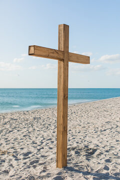 A wooden cross on the beach with blue skies 