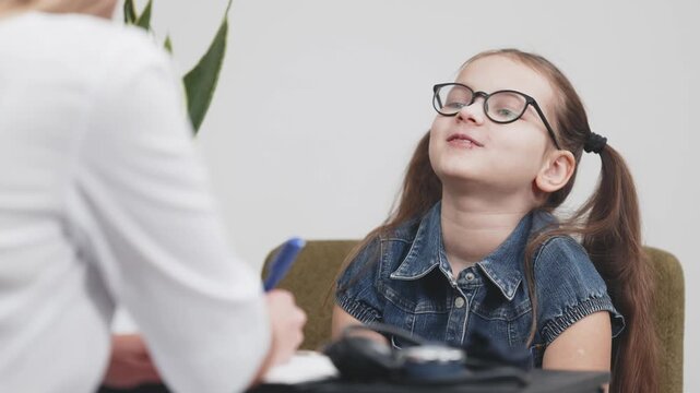 Child smiles during a healthcare consultation as professional takes notes in a clinic. Concept child health, pediatric consultation, medical care