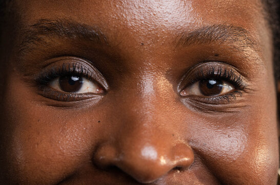 Female facing, looking into camera in studio close-up, showing eyes, lashes, brows, skin, mole