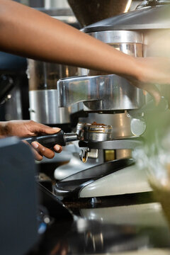 Espresso portafilter locking into group head on reflective cafe counter, warm metal highlights
