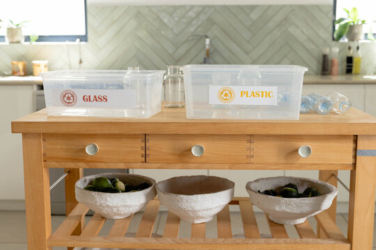 Wooden island is holding recycling bins labeled GLASS and PLASTIC near sink, pulp bowls with limes