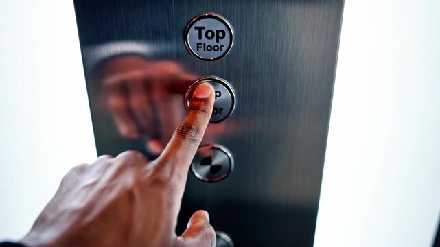 A hand pressing the top floor button on an elevator control panel