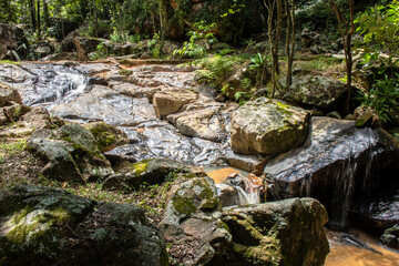 A small, serene waterfall cascades over dark, glistening rocks in a continuous, gentle flow, capturing the pure, raw beauty of nature in motion in Brazil. © AlfRibeiro