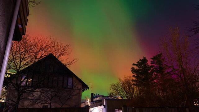 4K Timelapse of rare Green and Pink Aurora Borealis over Reykjavik Center Houses and Trees.