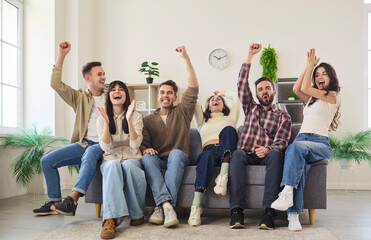 Friends fans celebrate football on TV home. A group of young people on a sofa, cheering at a sport...