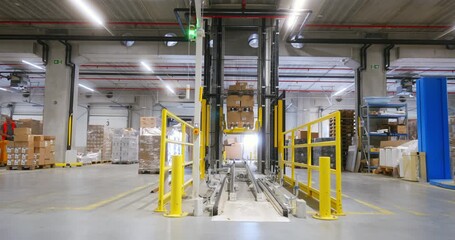 Autonomous lift operates in a logistics warehouse as it loads and unloads goods at various times during the day - Powered by Adobe