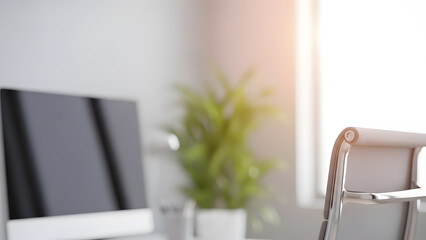 A blurred view of a bright and clean modern office interior with a desk chair and computer